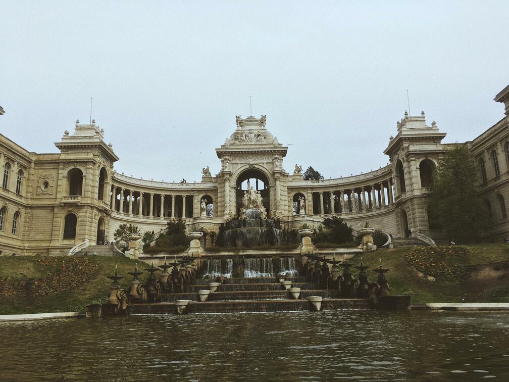 Vue en contre-plongée d'un bassin et sa fontaine entourés par une structure architecturale.